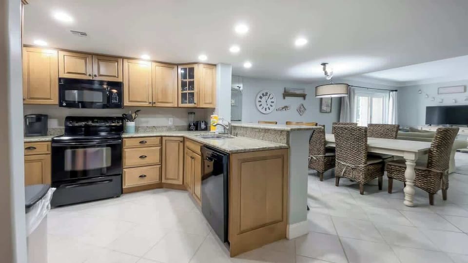 Features warm wood cabinetry, granite countertops, and modern black appliances