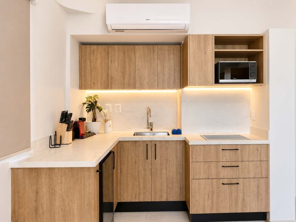 Sleek kitchenette with warm wood cabinets and a microwave, everything you need to cook in and settle