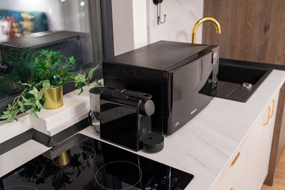 Induction cooktop, microwave and espresso machine along with capsules in the modern open-space kitchen