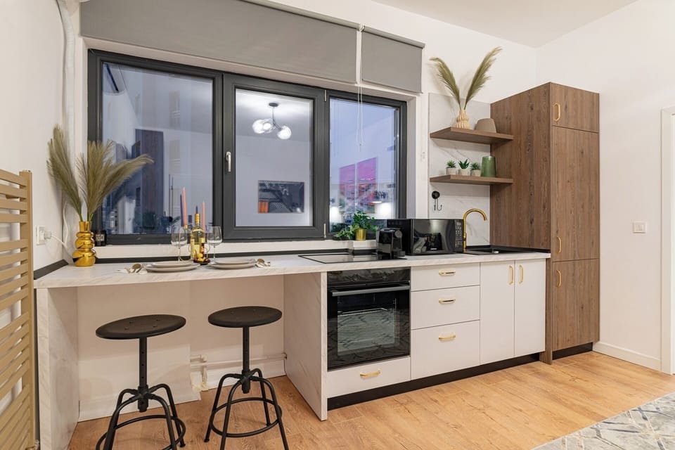 Open-space kitchen equipped with induction stove, electric oven, microwave, mini-fridge, chairs, espresso machine and basic condiments