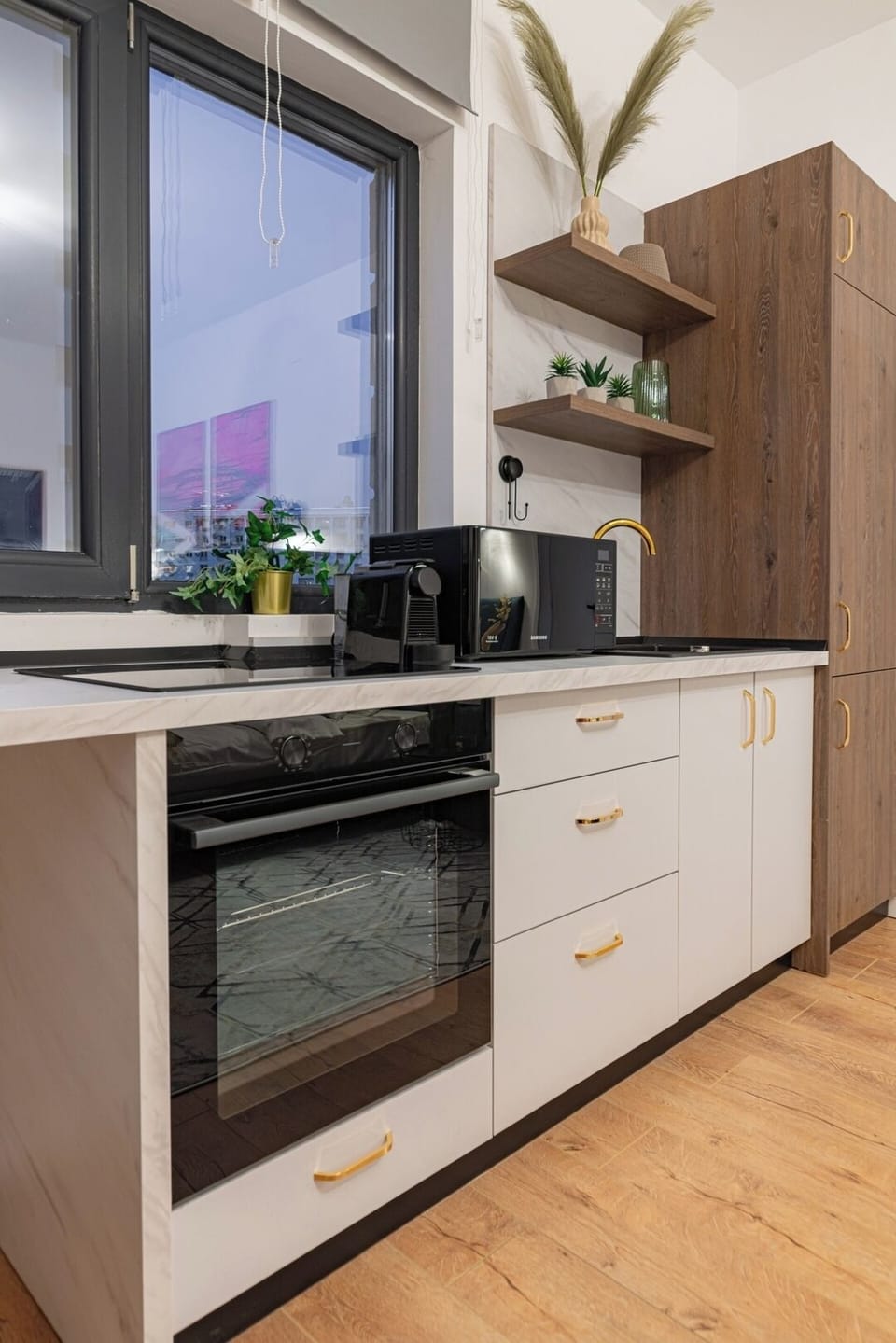 Open-space kitchen equipped with induction stove, electric oven, microwave, mini-fridge, chairs, espresso machine and basic condiments