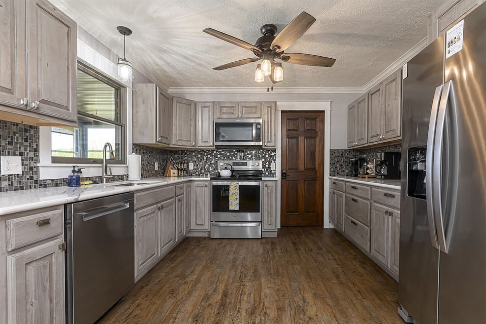 Modern kitchen with stainless steel appliances and wooden floors.