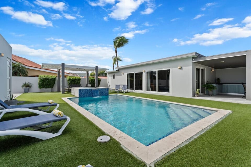 Enjoy the tranquil ambiance of the garden as you lounge by the pool in this serene outdoor oasis.