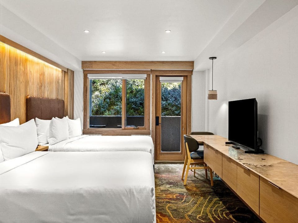 A tranquil room featuring plush bedding, warm wooden accents, and a door leading to an outdoor space, creating a harmonious connection with nature.