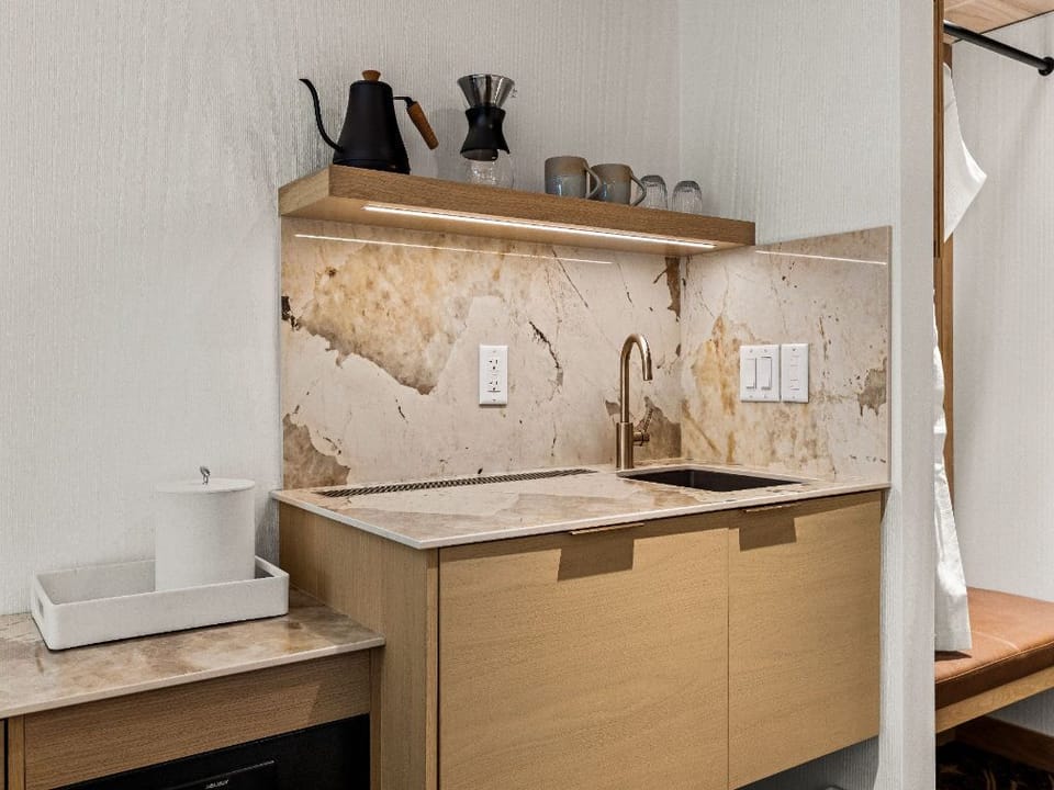 A modern kitchenette with natural wood textures and thoughtful design, providing a cozy and functional space for light meal preparation.
