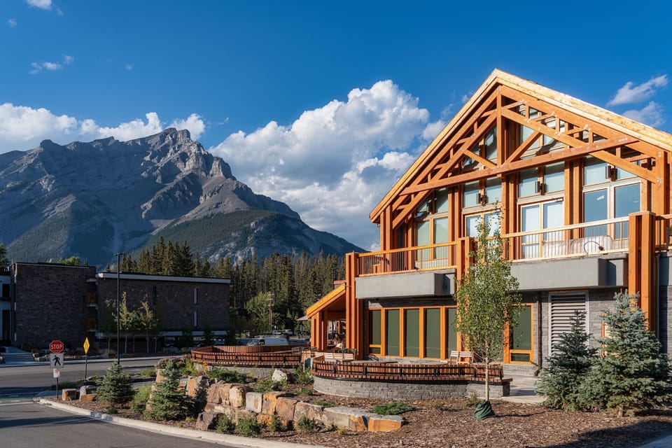 Your alpine retreat, with striking timber architecture rising beneath a wide blue sky.