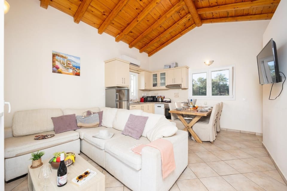 Open-plan living room with sofa, dining area, kitchen, A/C, WiFi internet, and satellite TV