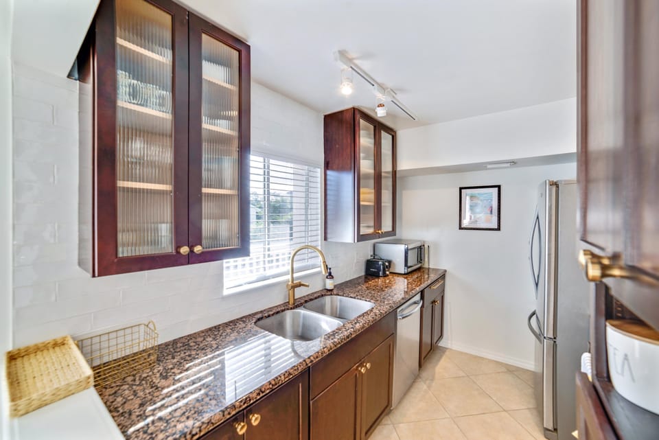 Enjoy cooking in this well-appointed kitchen, where large windows and rich cabinetry create a bright, elegant space.