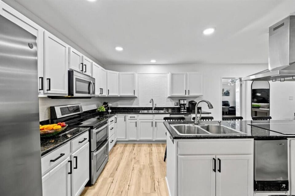 Well-stocked kitchen featuring two sinks, both drip and Keurig coffee makers, two double ovens, eight burners, a microwave, an ice maker, Ninja blender, an air fryer, electric kettle, a 4 slice toaster, and four bar chairs for chatting with the chef.