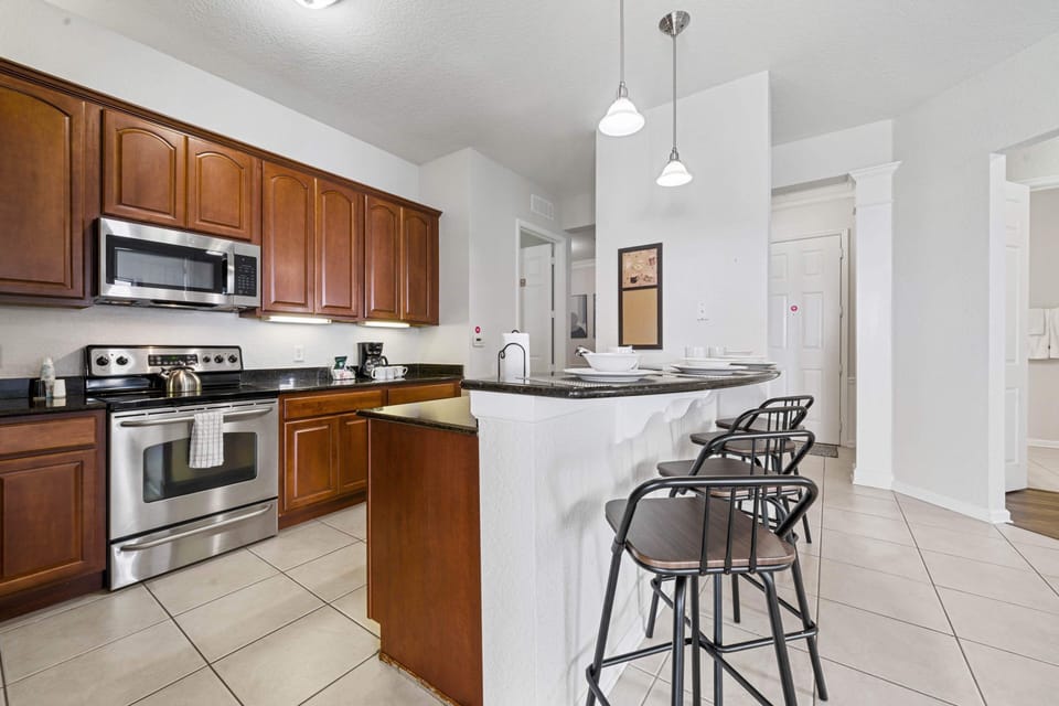 - Kitchen featuring stainless steel appliances, granite countertops, & warm wood cabinetry - Breakfast bar with stylish barstools is perfect for quick meals - Designed for both function & style, making meal preparation a breeze during your stay