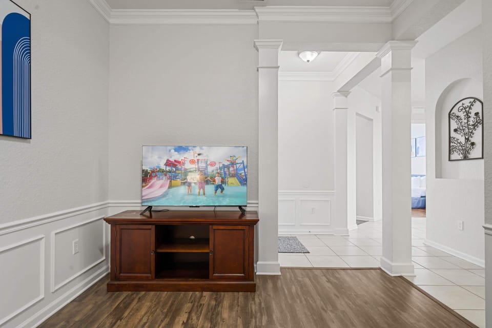 - Entertainment corner with a smart TV & classic wooden console, perfect for family movie nights - Located in a beautifully designed space with elegant wainscoting & hardwood floors - Thoughtfully positioned for a cozy & immersive viewing experience