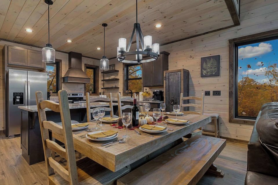 rustic dining area with wooden table set for six and modern kitchen in the background