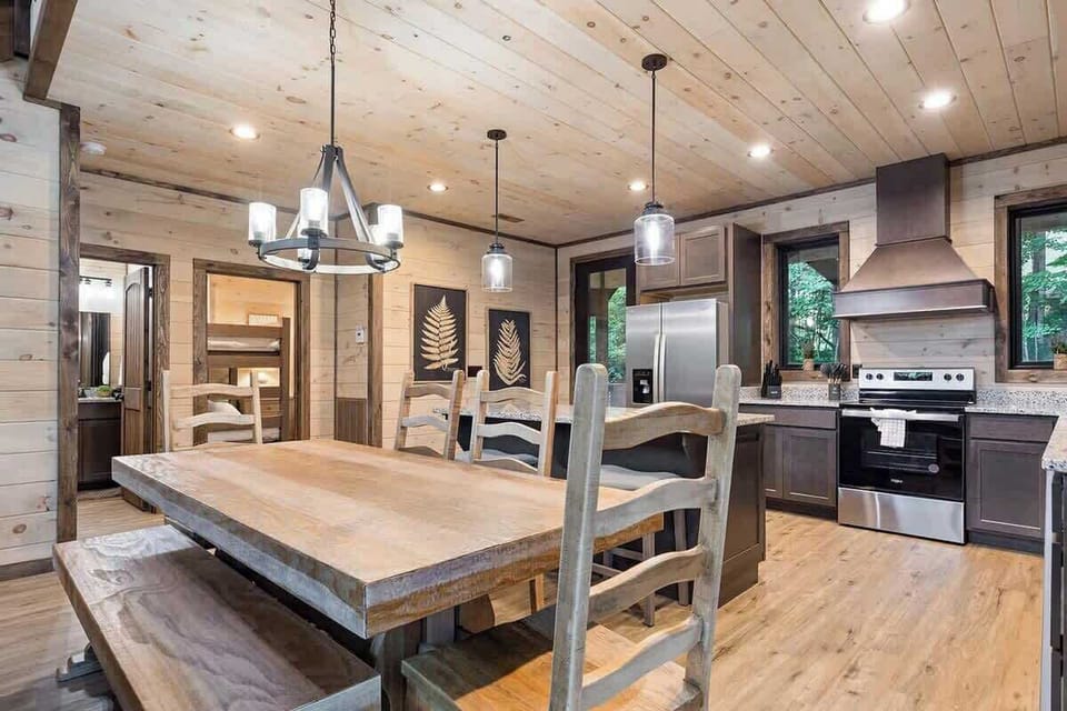 Rustic kitchen and dining area with wooden furnishings and stainless steel appliances.