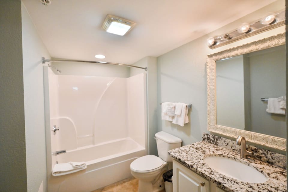 Elegant full bathroom featuring beautiful granite accents and a large mirror.