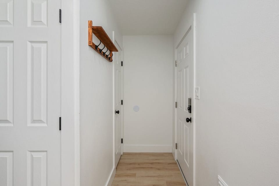 Minimalist hallway with wood floors, white doors, and coat rack.