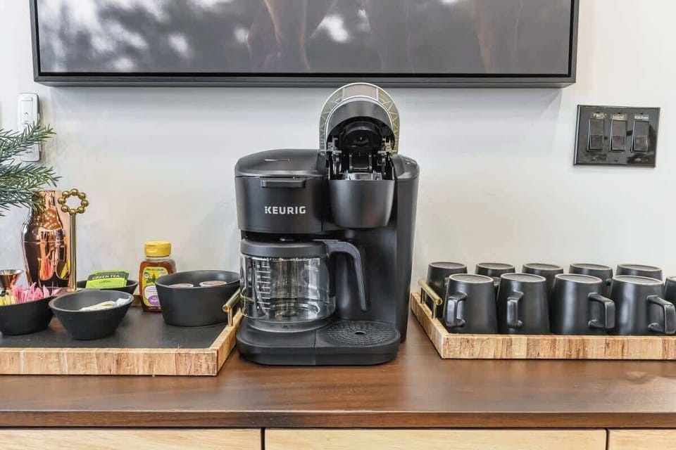 Modern coffee station with a Keurig machine and matching black mugs for convenient brewing.