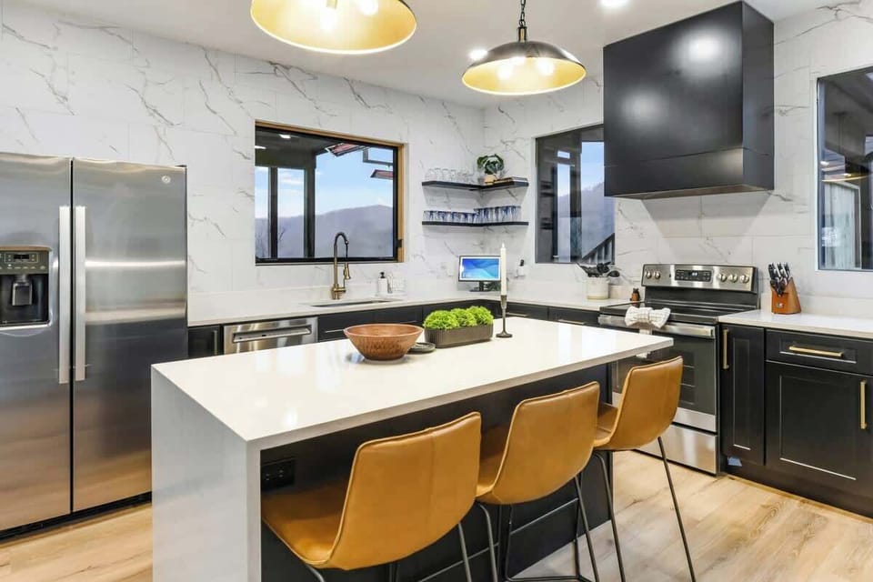 Modern kitchen with marble backsplash, black cabinetry, and a large island with seating.