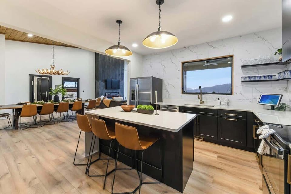 Modern kitchen with a large island and seating overlooking the dining and living areas.