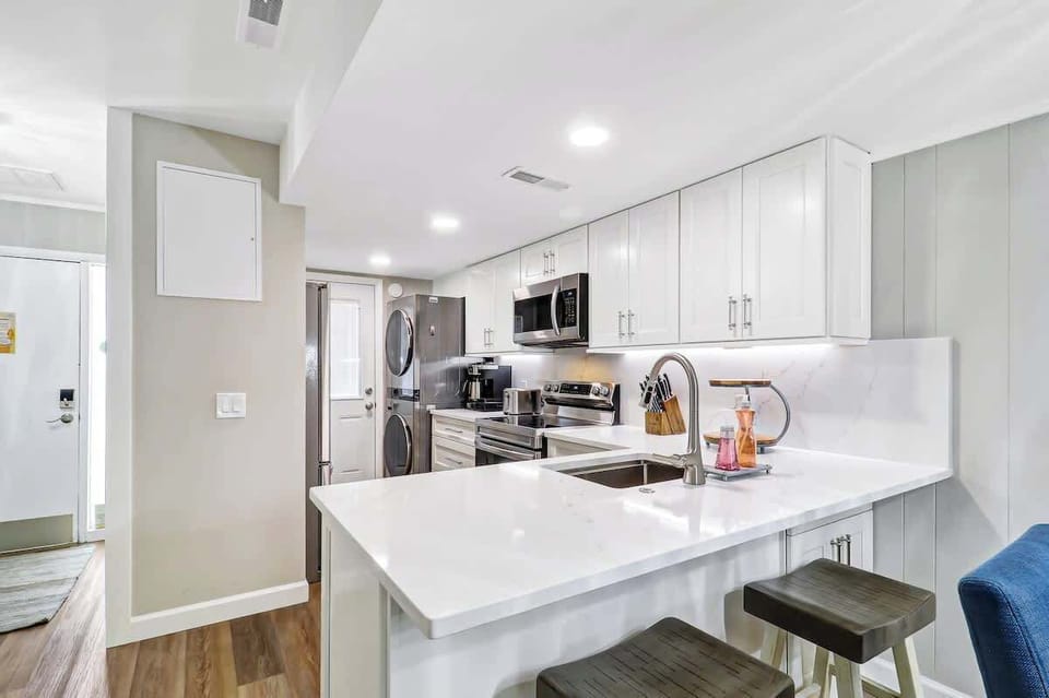 Your sleek white kitchen features modern appliances and a breakfast bar where you can sip morning coffee while planning your day.