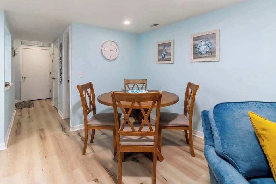 Cozy dining area with a round wooden table and sea-themed decor on soft blue walls.