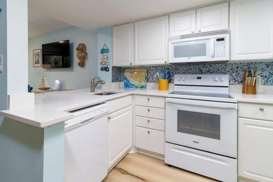 Modern kitchen with white cabinetry and blue mosaic tile backsplash
