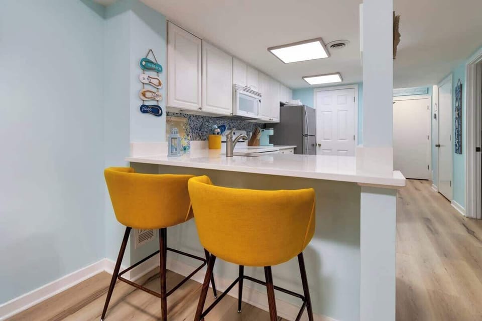 Bright kitchen with yellow bar stools and a light blue coastal theme.