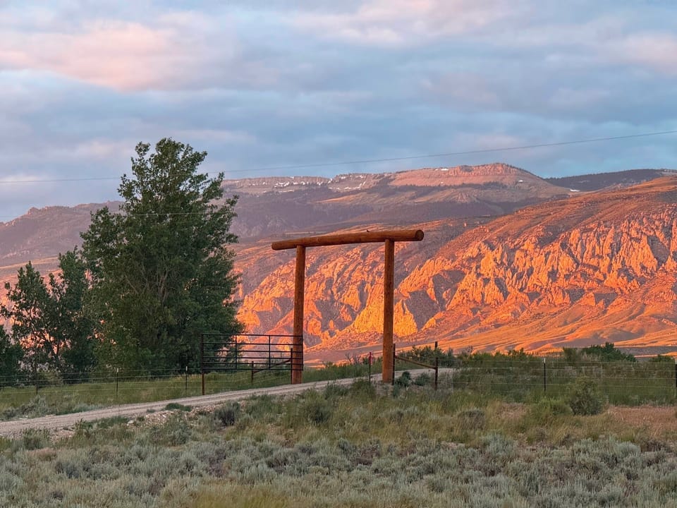 Ranch gate to Ever Sky Cabins with the sun illuminating the Bighorn Mountains