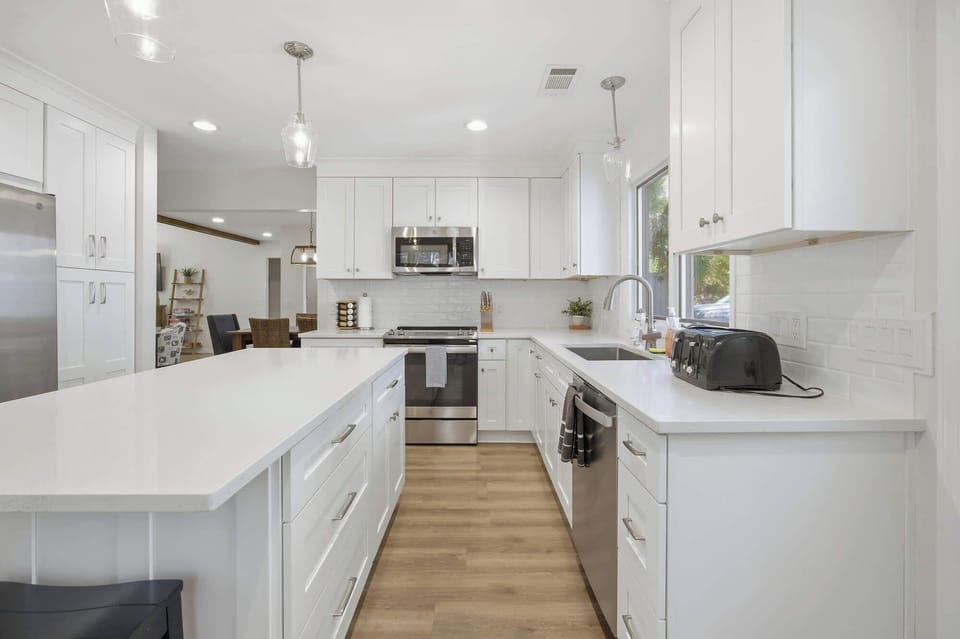 Modern kitchen with white cabinetry, stainless steel appliances, and a spacious island for cooking and dining.