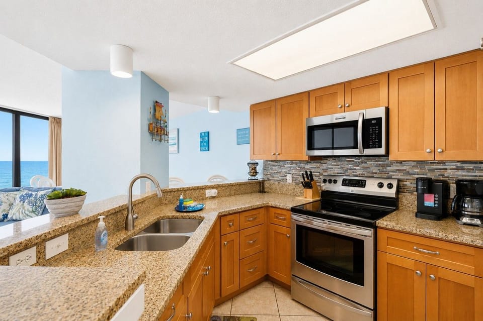 Full Kitchen with Drip and K-cup coffee makers, stove / oven / Microwave range / double undermount sinks, granite countertops, full-sized refrigerator with icemaker and ocean-view.  Bar top with 2 stools for extra seating