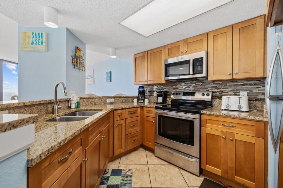 Full Kitchen with Drip and K-cup coffee makers, stove / oven / Microwave range / double undermount sinks, granite countertops, full-sized refrigerator with icemaker and ocean-view.  Bar top with 2 stools for extra seating