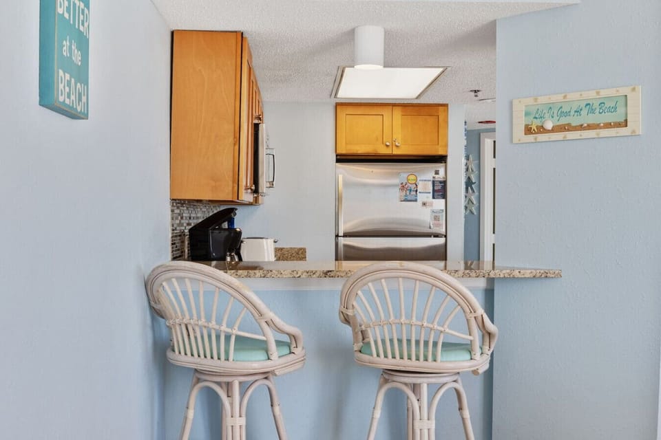 Bar-top stool overlooking the kitchen and oceanfront dining area.  Perfect for evening drinks or extended dining options.  Beautifully decorated beach theme.  Unwind in the evening at this in-house bar.