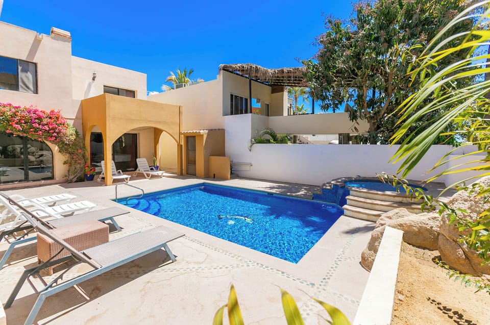 The outdoor area boasts a sparkling pool, a relaxing jacuzzi, and a spacious patio, perfect for lounging, entertaining, or enjoying the beautiful Cabo weather.