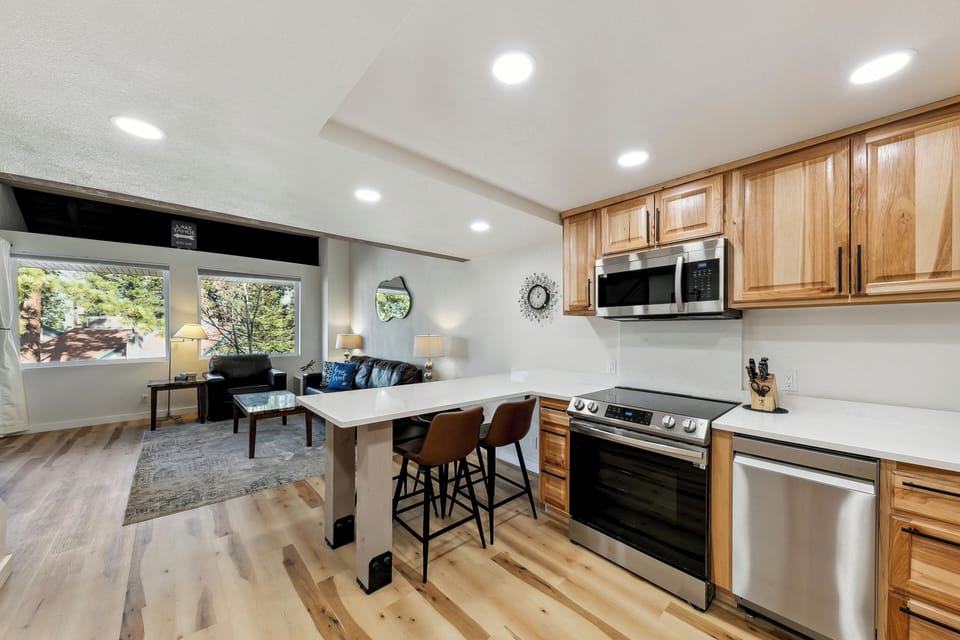 Your open-concept space combines kitchen and living areas with warm wood cabinetry, modern appliances, and cozy seating for relaxing after mountain adventures.