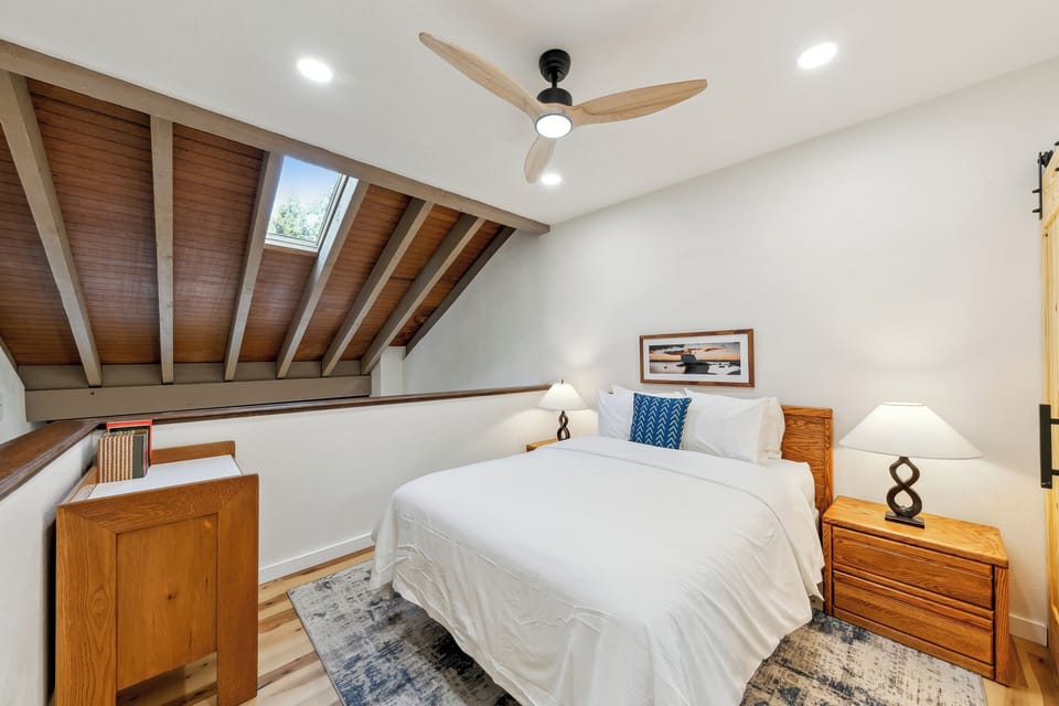 Drift off to sleep beneath your private skylight in this cozy loft bedroom, where natural light and exposed wooden beams create a perfect retreat.