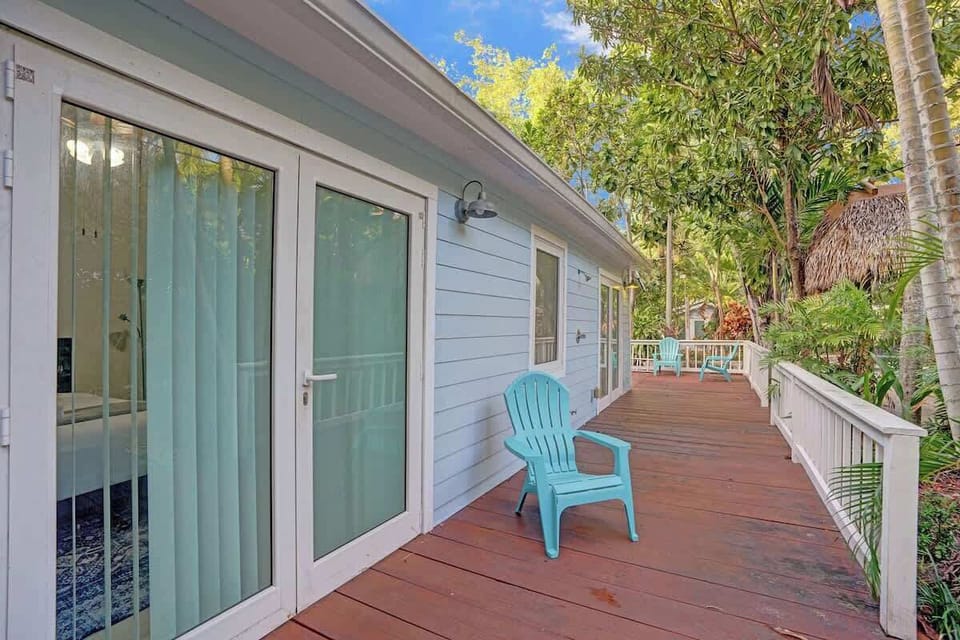 Side deck with turquoise Adirondack chair and sliding glass door connecting to the bedroom.