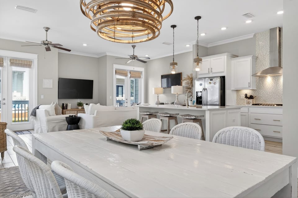 Sunlit dining space with coastal style—gather for meals, game nights, and easy indoor-outdoor living just steps from the lounge area.