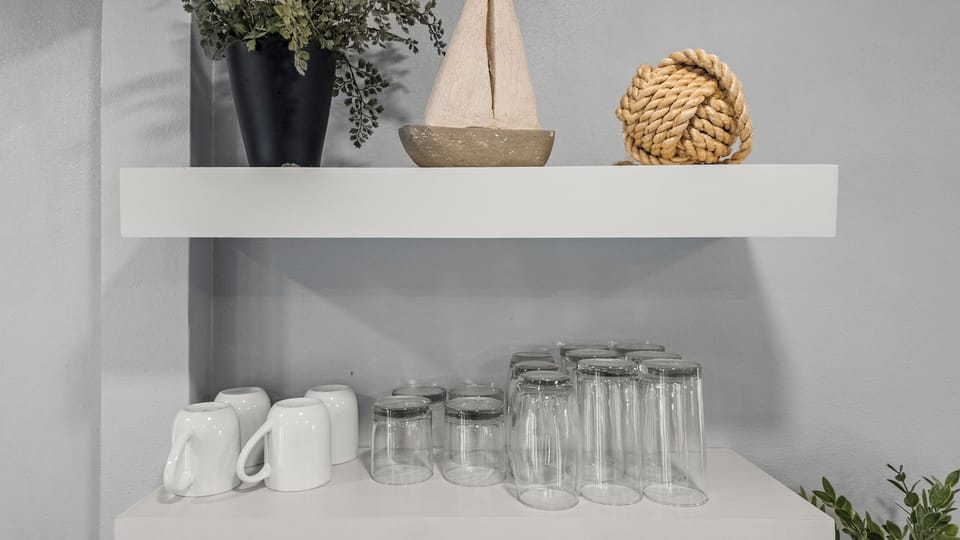 Mugs, mason jar glasses, and coastal details at The Lookout at R½ — open shelving stocked for every occasion, from morning coffee to evening drinks on the deck.