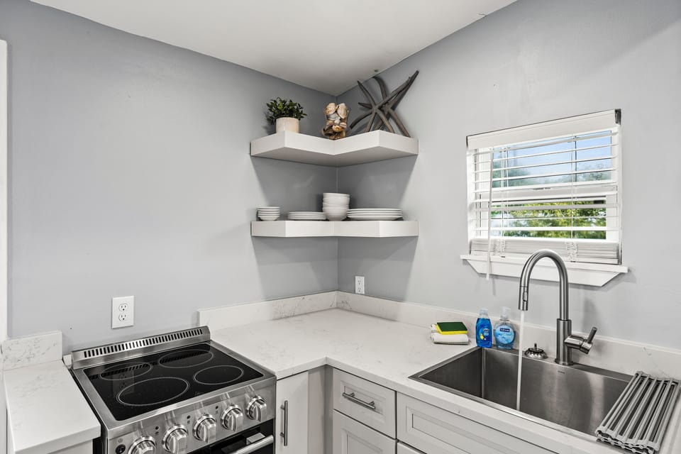 Kitchen details at The Lookout at R½ — stainless appliances, modern fixtures, open corner shelving, and generous counter space for cooking real meals on vacation.