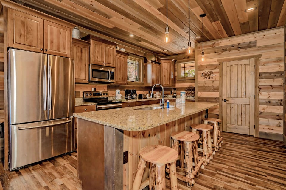 Rustic kitchen with wood cabinets, log stools, and cozy lighting.
