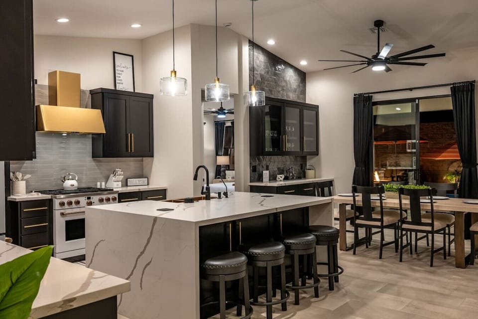 Luxury kitchen with gold accents, and a spacious island with bar seating. Features high-end appliances like a gas range, Café coffee maker, toaster oven, and Vitamix blender, perfect for cooking enthusiasts seeking elegance and functionality