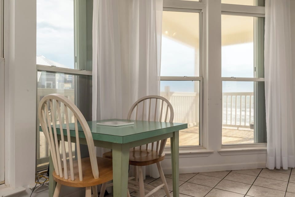 Enjoy meals with an ocean view at your charming dining table, where sunlight streams through large windows.
