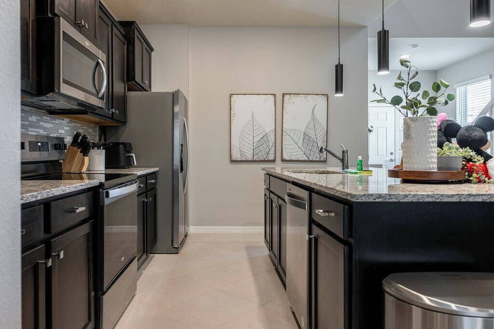 Step into this contemporary kitchen featuring sleek black cabinetry that complements the polished granite countertops. The space is well-lit, showcasing elegant decor pieces and a touch of greenery for a refreshing vibe.