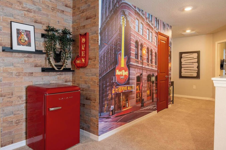 Welcome to a vibrant entryway with a striking brick wall and a bold red retro refrigerator that adds color. The unique mural of a bustling street scene invites warmth and creativity, ensuring you feel right at home.