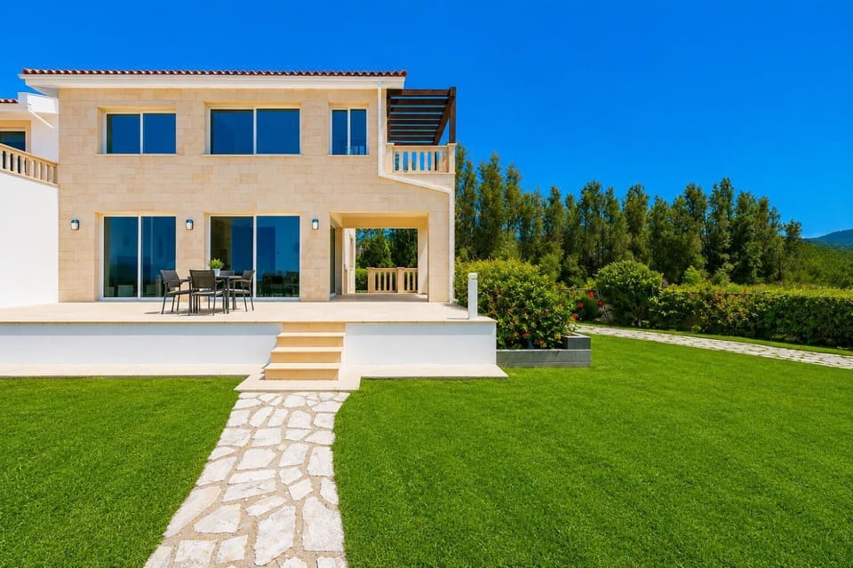 A straight-on exterior view of the multi-level coastal house, showcasing its modern architecture and connection to the lawn area.