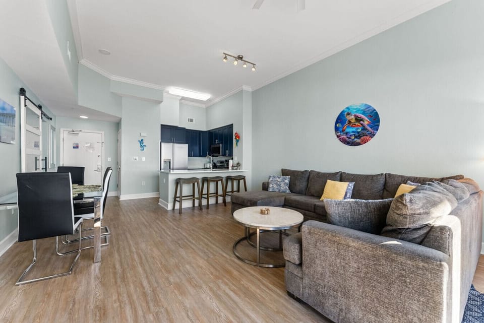 Wide-angle view of the living room showcasing the open layout, breakfast bar, and seating for everyone.