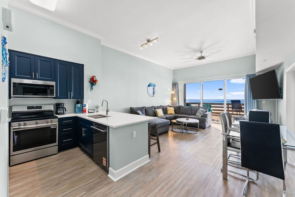 Open-concept living space with modern kitchen, dining area, and direct access to the beachfront balcony.