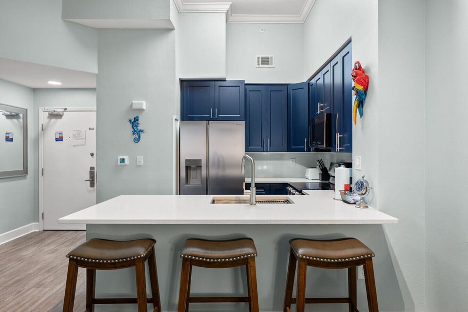 Modern coastal kitchen with navy cabinets, stainless appliances, and a spacious island with seating for three.