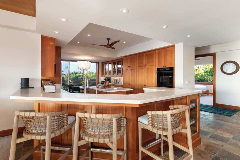 Your spacious kitchen invites culinary adventures with warm wood cabinetry, marble countertops, and island seating for memorable meals together.