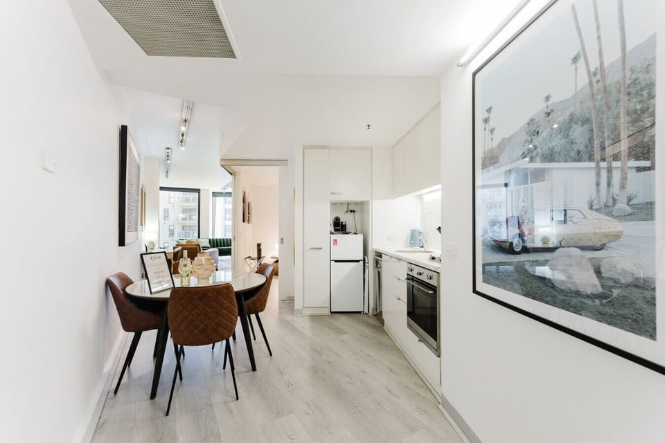 Bright dining area connected to a compact, modern kitchen.