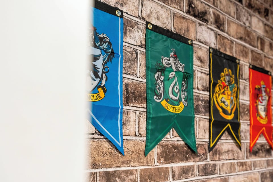 Step into a unique atmosphere adorned with vibrant house banners against a rustic brick wall, creating a playful and immersive backdrop. The rich colors and textured surfaces invite conversation and discovery, enhancing your stay.